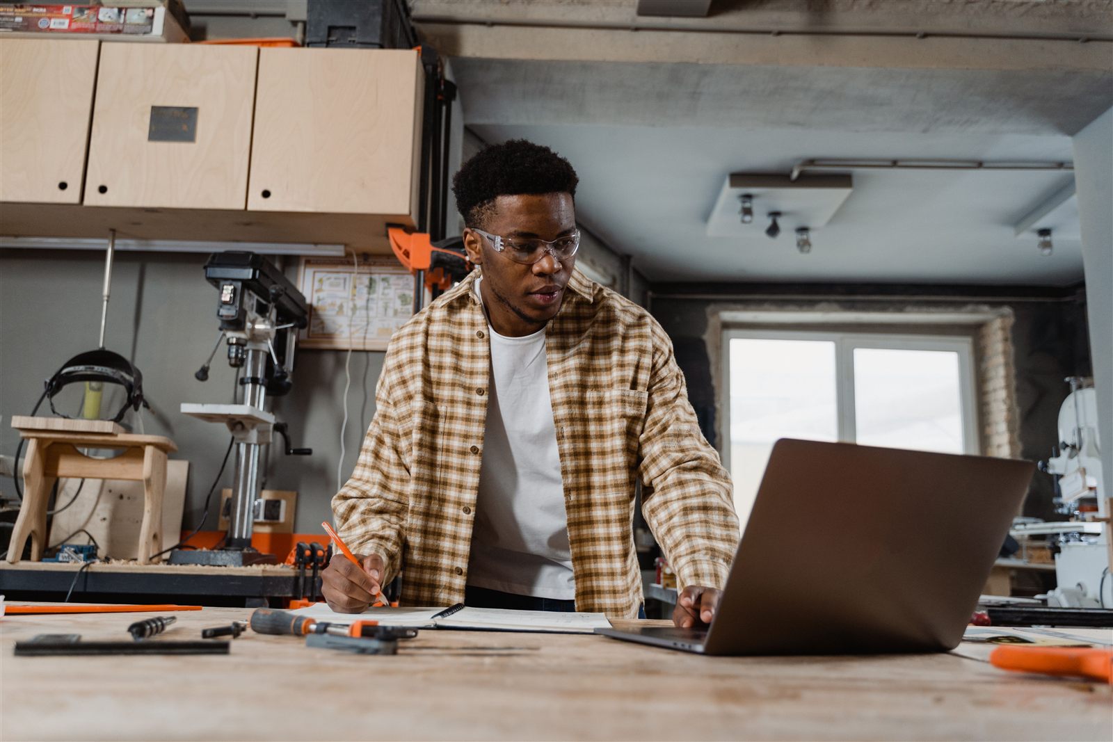 Carpenter reviewing plans on a laptop in a workshop